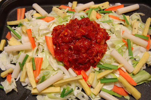 強火で熱した鉄板にサラダ油をひき、最初にキャベツをのせ、そのほかの野菜とトッポッキをのせ、最後に（1）の鶏肉をのせる。