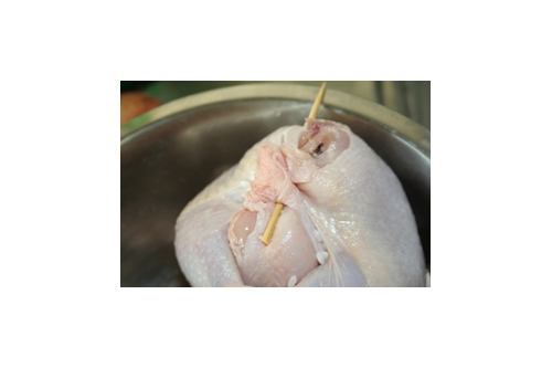 鶏のお腹に、もち米とナツメを入れ、竹串か楊枝で口を縫うようにふさぐ。