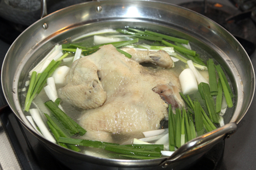 （2）の鶏肉が骨ごとはさみで切れるくらいやわらかく煮えたら鶏肉以外の具を取り出し、じゃがいも、長ねぎ、ニラ、トッポッキを加える。じゃがいもに火が通ったら、鶏肉を食べやすくはさみで切る。