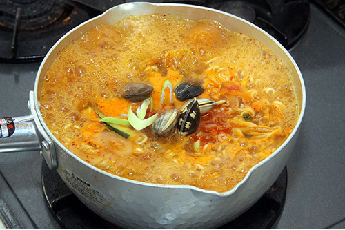 水を加えて強火にかけ、煮立ったら麺と粉末スープを加え強～中火で3分ほど煮込む。
あさりと長ねぎを加えて1分ほど煮込んだら、こしょうをふって器に盛る。