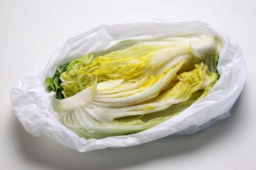 白菜は縦半分に切り、葉を1枚ずつめくりながら芯の部分に塩をふる。最後に芯の側面にも塩をふり、ビニール袋に入れて空気が入らないように口を縛る。時々上下を返したりもみながら2時間ほどおく。