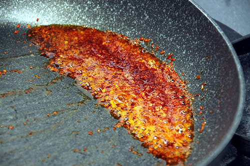 フライパンにごま油と唐辛子、にんにくを入れ、フライパンを傾けて焦げないように注意しながら弱火でじっくり炒めて韓国ラー油を作る。