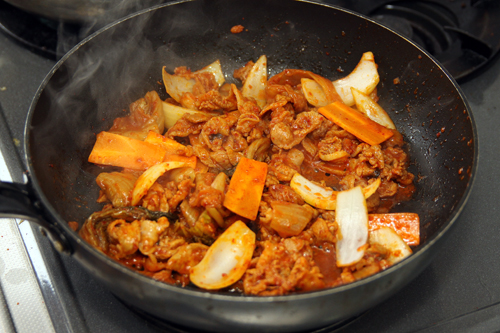 熱したフライパンに（2）を入れて2～3分、豚肉に火が通るまで炒めて弱火にする。玉ねぎと人参を加え、さらに2～3分炒める。